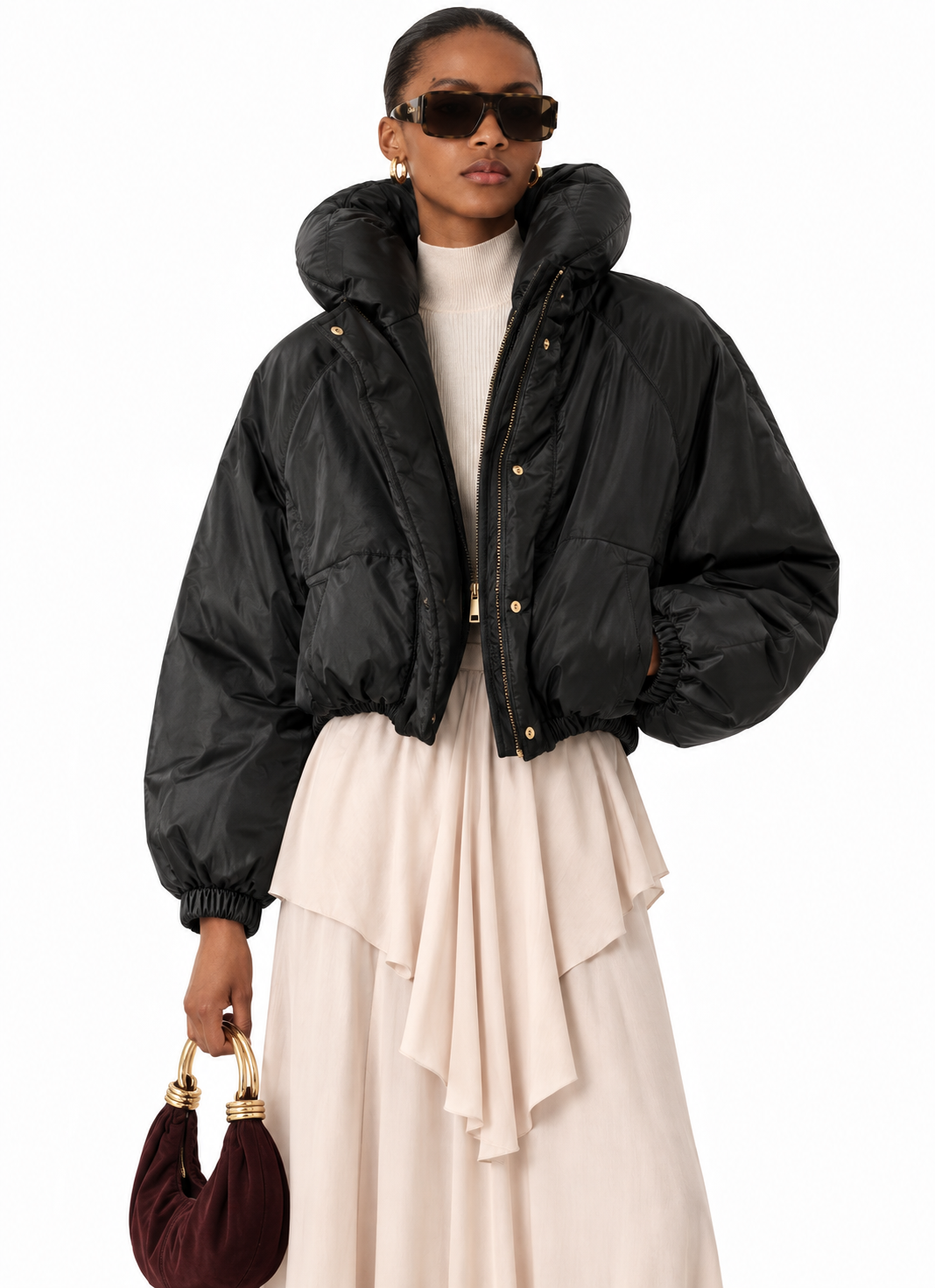 Model wearing women's black cropped hooded puffer jacket with a cream skirt
